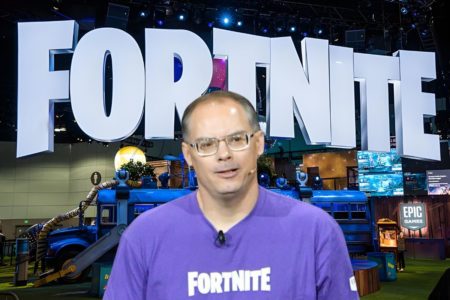 Le créateur de Fortnite devant une grande affiche du jeu.