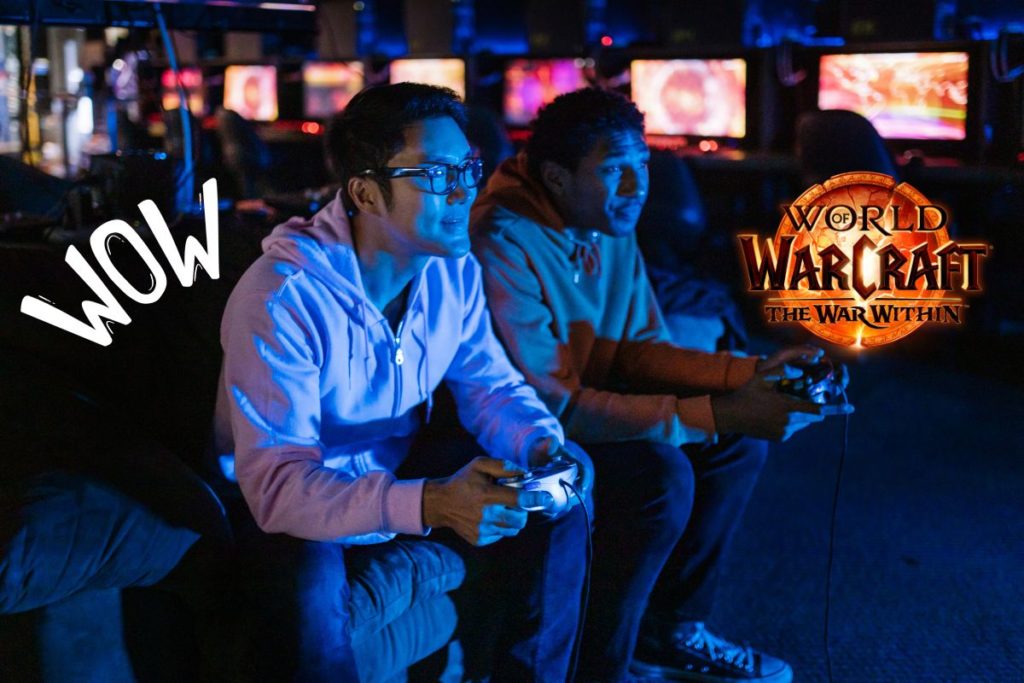 Deux joueurs concentrés jouant à World of Warcraft The War Within dans une salle de jeux éclairée en bleu.