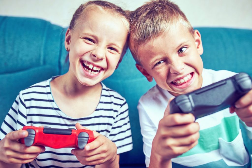 Deux enfants souriants jouant aux jeux vidéo avec des manettes.