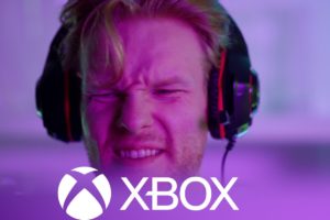 Un joueur avec un casque de gaming montrant une expression contrariée avec le logo Xbox en avant-plan.